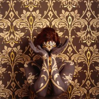 Artista se camufla em papéis de parede